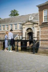 Twee mensen bekijken een informatiebord voor het kasteel van Breda